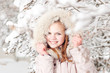 Beautiful young girl in a hood on a background a snow-bound tree