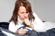 Frau liegt krank und heustend im Bett