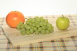 Fresh green grapes, apple and grapefruit on a table