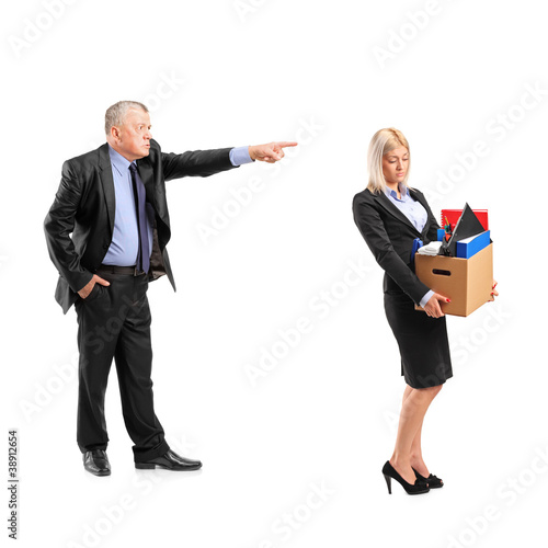 Photo: Angry boss firing a woman in a suit carrying a box of personal i Angry boss firing a woman in a suit carrying a box of personal i