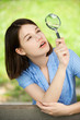 Young woman looks through magnifier