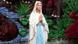 A praying virgin mary statue with  fountain background
