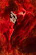 Photo: Beautiful woman in red waving silk dress as a fire flame. Lookin Beautiful woman in red waving silk dress as a fire flame. Lookin