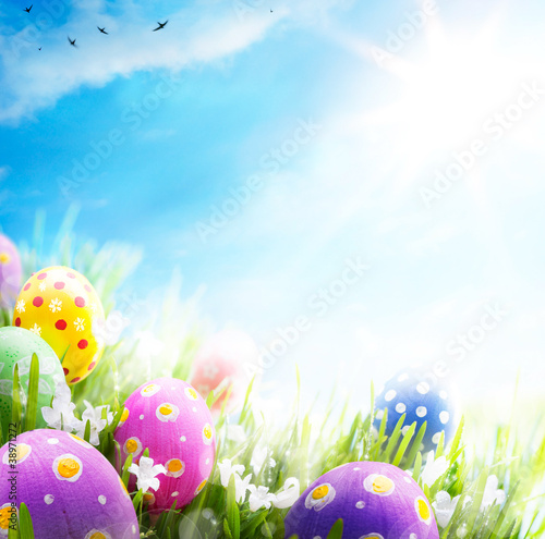 Photo: Art Easter eggs decorated with flowers in the grass on blue sky Art Easter eggs decorated with flowers in the grass on blue sky