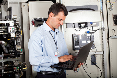 Foto: industrial programmer checking computerized machine status industrial programmer checking computerized machine status