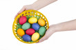 hands holding up a basket full with colored easter eggs