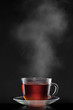 cup with hot tea and steam on black