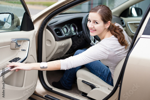 Photo: Pretty young woman driving her brand new car Pretty young woman driving her brand new car