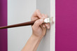 Weibliche Hand bessert Wandfarbe aus