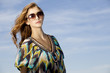 beautiful girl in sunglasses on background blue sky
