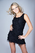 Beautiful young blonde woman wearing black dress over gray