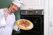 Photo: young chef with italian pizza in kitchen young chef with italian pizza in kitchen