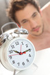 Ringing alarm clock waking up a man