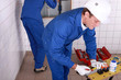 Plumbers working in a tiled room