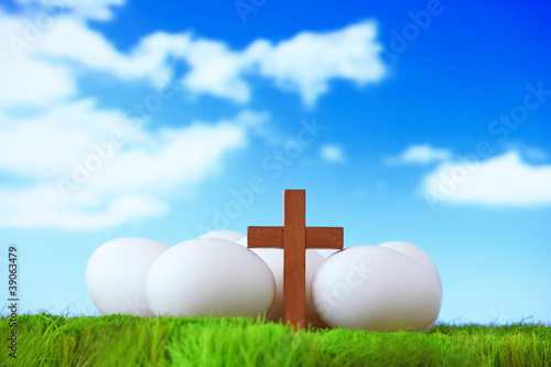 Photo: white eggs and wood cross on grass with blue sky white eggs and wood cross on grass with blue sky