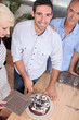 Man smiling at camera as he cut a chocolate cake