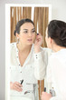 Young woman applying mascara in front of a bathroom mirror