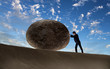Businessman rolling a giant stone
