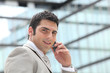 Entrepreneur using a cellphone outside a mirrored building