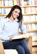 smiling female student with book in hands in a bookstore - model