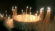 Donne che prega in chiesa, candelle accese.
