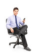 Young businessman sitting on a chair and holding a mobile phone Young businessman sitting on a chair and holding a mobile phone