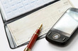 A pen and a mobile phone over a checkbook