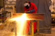 Welder bends to cut metal beam. Welder bends to cut metal beam.