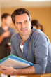 Portrait of man standing in building hall with files