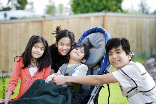 Photo: Three children surrounding a small disabled child in wheelchair Three children surrounding a small disabled child in wheelchair