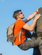 Young man in glasses with backpack climbing