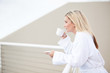 young woman in bathrobe drinking coffee on balcony