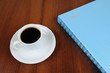 Foto: Cup of coffee and notebook on table Cup of coffee and notebook on table