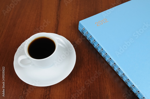 Foto: Cup of coffee and notebook on table Cup of coffee and notebook on table