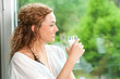 Topmodel mit Glas Milch schaut aus dem Fenster