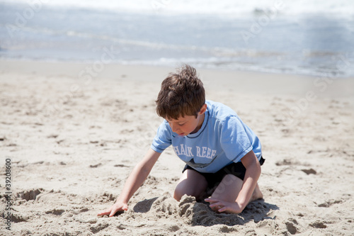 Photo: Little Boy Playing with sand on the Beach Little Boy Playing with sand on the Beach