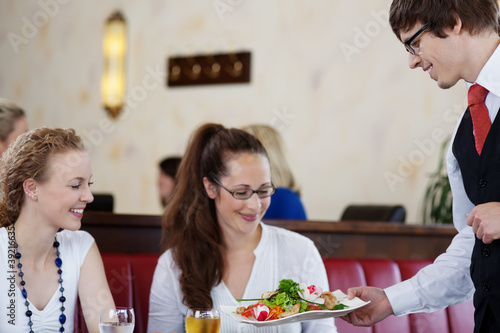 Photo: freundlicher kellner serviert einen salat freundlicher kellner serviert einen salat