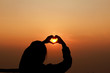 Hands make heart shape before Sunrise .