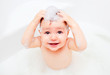 Happy child washing in a bathroom in foam