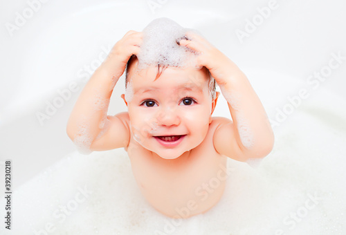Photo: Happy child washing in a bathroom in foam Happy child washing in a bathroom in foam