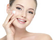 Beautiful smiling woman applying  cream on cheek