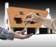Man is handing a house key to a other man in the shape of the ho