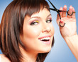 Attractive smiling girl with scissors, cutting her hair