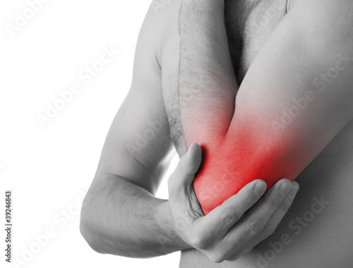 Photo: Rear view of a young man holding his elbow in pain, isolated on Rear view of a young man holding his elbow in pain, isolated on