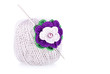Grey ball of cotton yarn with knitted flower on white background