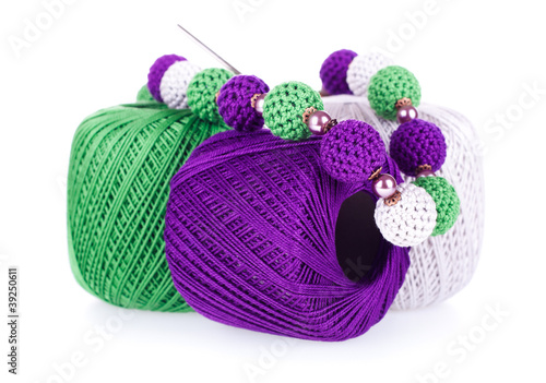 Photo: Three balls of cotton yarn with necklace on white background Three balls of cotton yarn with necklace on white background