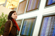 Photo: Beautiful young tourist in the airport looking at the flight boa Beautiful young tourist in the airport looking at the flight boa