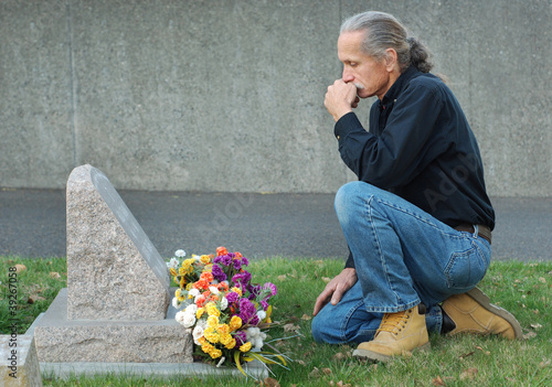 Photo: Man sitting at gravesite Man sitting at gravesite