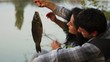 Happy young couple caught a fish at sunset