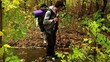 Young hiking couple crossing a stream in autumn forest